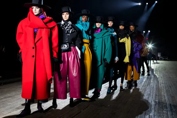 Side-by-side fashion runway looks featuring models in bold red pants, black jackets with gold detailing, and statement hats, showcasing high-fashion inspired designs from different eras.